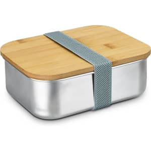 A stainless steel lunch box with a bamboo lid, secured by a grey elastic strap. It has a shiny silver base.