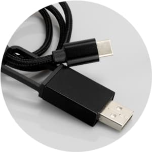 A braided charging cable in black, featuring USB and USB-C connectors, displayed on a grey background.