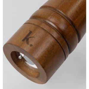 A wooden pepper mill with a smooth finish, featuring a circular base and a logo engraved on the side.