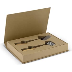 A kitchen slicer and grater set in a brown cardboard box, featuring metallic tools and a branded logo.