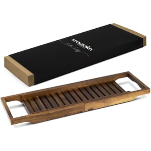 A wooden bath caddy in a warm brown finish, alongside its elegant black packaging with a logo.