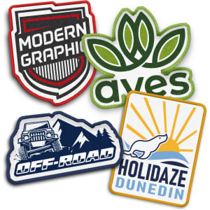A selection of four custom woven patches in various shapes and colours, featuring logos and designs.