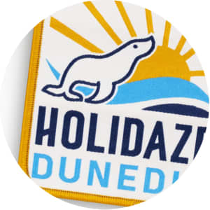 A woven patch featuring a yellow and blue design with a sun and a playful seal silhouette.
