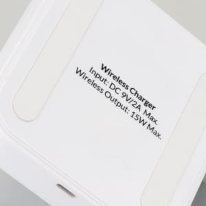 A wireless charging stand in white with a smooth surface and a branding logo on the base.