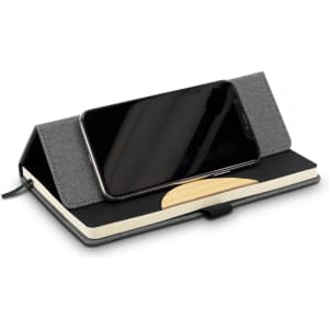 A grey notebook with a phone resting on its cover, featuring a smooth surface and a decorative design.