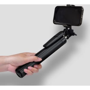 A black selfie stick tripod held in a hand, featuring a phone holder at the top.