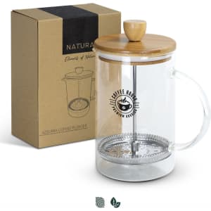 A glass coffee plunger with a bamboo lid sits next to its kraft box packaging.