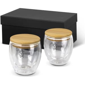A drinkware set featuring two clear glass mugs with bamboo lids, presented in a black box.