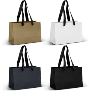 Four small ribbon handle paper bags in gold, white, navy, and black, featuring black handles and a simple design.