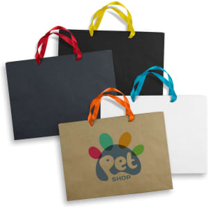 An assortment of extra large paper bags in black, brown, white, and vibrant colours, featuring ribbon handles.