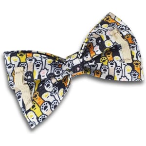 A pet bow tie featuring a colourful pattern of ghosts and paw prints on a dark background. It has a loop for attachment.