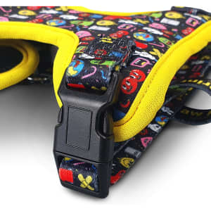 A pet harness in black with bright, colourful patterns and yellow accents, featuring a plastic buckle.