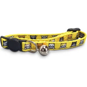 A yellow cat collar featuring a pattern of cats, with a silver bell and adjustable clasp. It has a logo on it.
