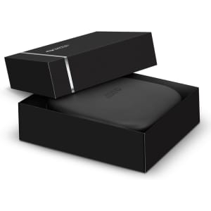 A black gift box partially open, revealing a sleek black headphone case inside. The box features a simple logo.
