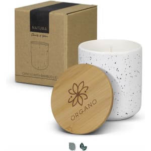 A white speckled candle in a ceramic holder with a bamboo lid, alongside its cardboard packaging.