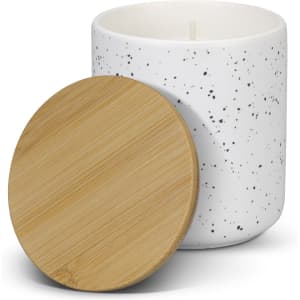A white candle with a speckled design and a natural bamboo lid.
