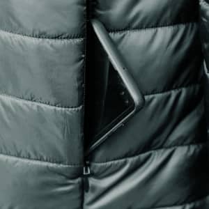 A puffer jacket with a zippered pocket, containing a smartphone, in a dark colour.