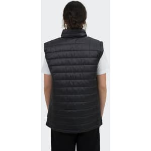 A women's puffer vest in black, featuring a high collar and a quilted design, worn over a white top.