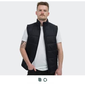 A man wearing a black puffer vest over a white t-shirt, standing against a plain background. The vest features a logo.