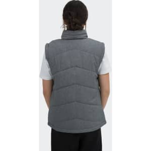 A women's puffer vest in grey with a high collar and quilted design, featuring a logo on the back.