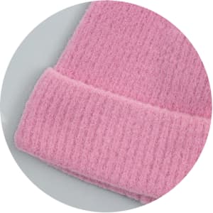 A pink brushed kids beanie with a textured, ribbed cuff and soft fabric. It features a logo on the tag.
