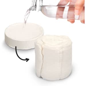 A compressed white towel next to a hand pouring water from a clear drink bottle. The towel appears in a circular shape.