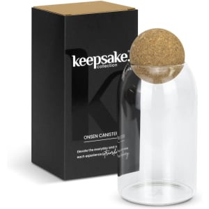 A glass canister with a cork lid, presented with a black box featuring a logo.