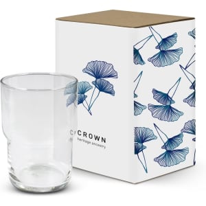 A stackable clear glass tumbler next to a decorative box featuring a floral design and a logo.