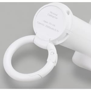 A white personal cooling fan with a carabiner clip and a circular base. It features a branding logo on the side.