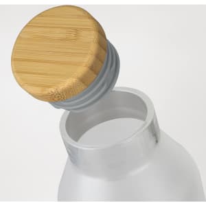 A drink bottle with a transparent body and a bamboo lid, featuring a grey seal.