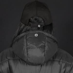 A black puffer jacket with a hood, worn by a person wearing a black cap, featuring a logo on the back.