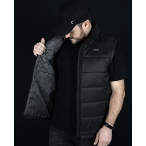 A man in a black Swiss Peak Urban Puffer Vest, holding it open to display the interior lining.