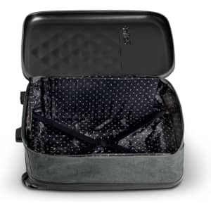 A small green wheeled suitcase with an unzipped black interior featuring a patterned lining. The suitcase has a logo.