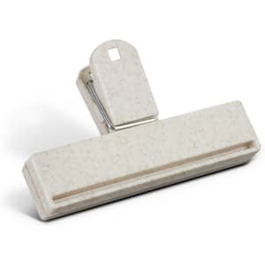A beige snack bag clip with a textured surface and a silver metal spring mechanism.