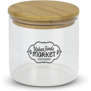 A large round glass storage canister with a bamboo lid and a decorative logo on the front.