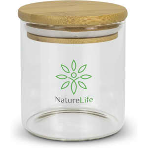 A small round glass storage canister with a bamboo lid and a green logo on the front.