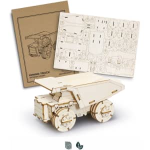 A wooden mining truck model in light timber, with assembly parts and instructions in the background.