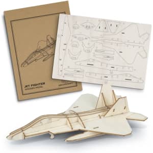 A wooden model of a jet fighter in light wood tones, alongside a die-cut sheet and packaging with a logo.
