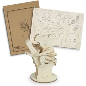 A wooden model of a koala clinging to a tree, accompanied by a cut-out sheet and packaging. Natural wood colour.