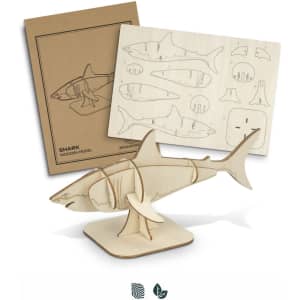 A wooden shark model in natural wood colour with assembly pieces and instructions displayed beside it.