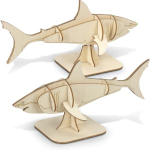 A natural wood model of a shark, featuring intricate cut-out designs, displayed on a flat base.