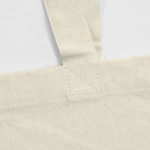 A cream-coloured tote bag with stitched handles and a visible logo. The fabric appears to be recycled cotton.