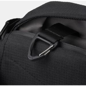 A close-up of a black sling bag featuring a sturdy zip and metal clip for attachment.