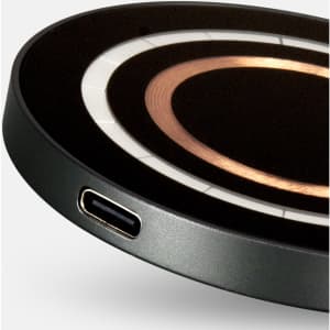 A round, black wireless charger with a copper centre and a USB-C port. It has a sleek, minimalist design.
