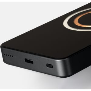 A black wireless charging power bank with a circular design and a USB-C port, featuring a logo.