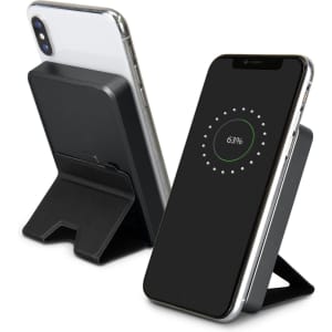 A black wireless charging power bank with a stand, featuring a smartphone displaying a charging indicator.