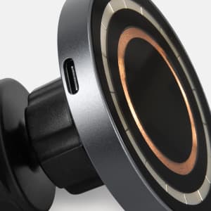 A wireless car charger in black and metallic silver, featuring a circular design and a charging port.