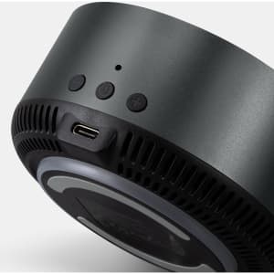 A wireless charging speaker in black with control buttons and a USB-C port. It features a sleek, circular design.