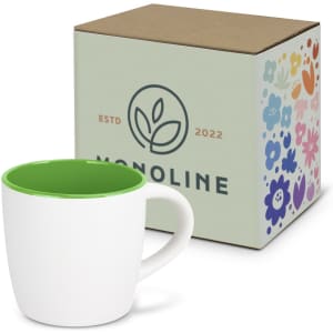 A two-tone coffee mug with a white exterior and green interior, next to a patterned cardboard box featuring a logo.