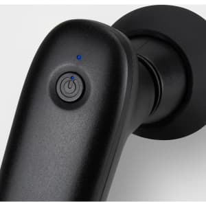 A compact handheld massager in black with a power button and a blue indicator light.